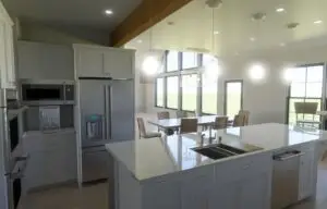 Spacious white kitchen with exposed beams, quartz island, and modern stainless steel appliances.