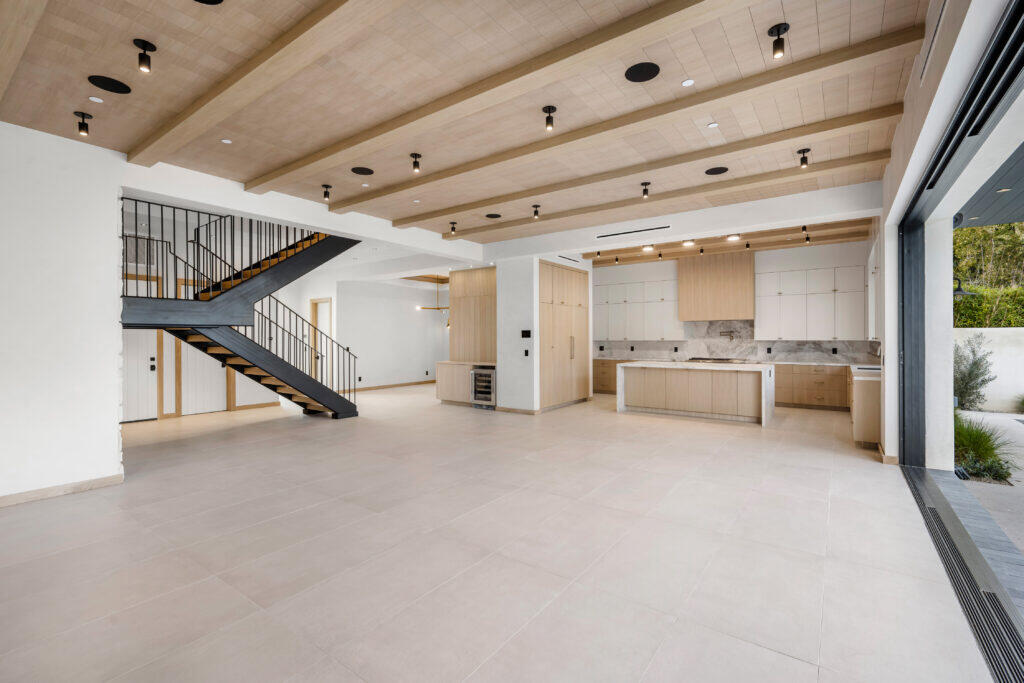 the interior of a house with an empty space and a staircase leading to the kitchen - Custom Homes